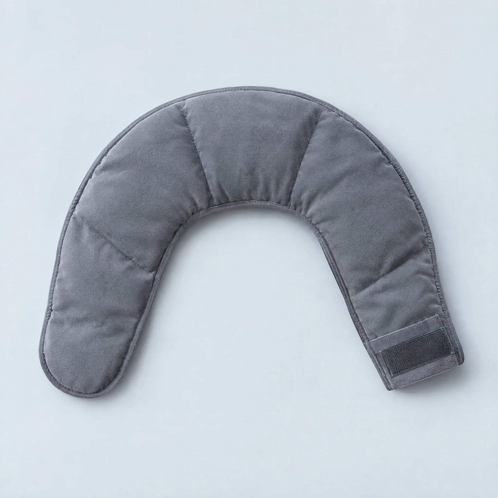 Curved slate gray quilted neck wrap with a hook-and-loop strap laid flat