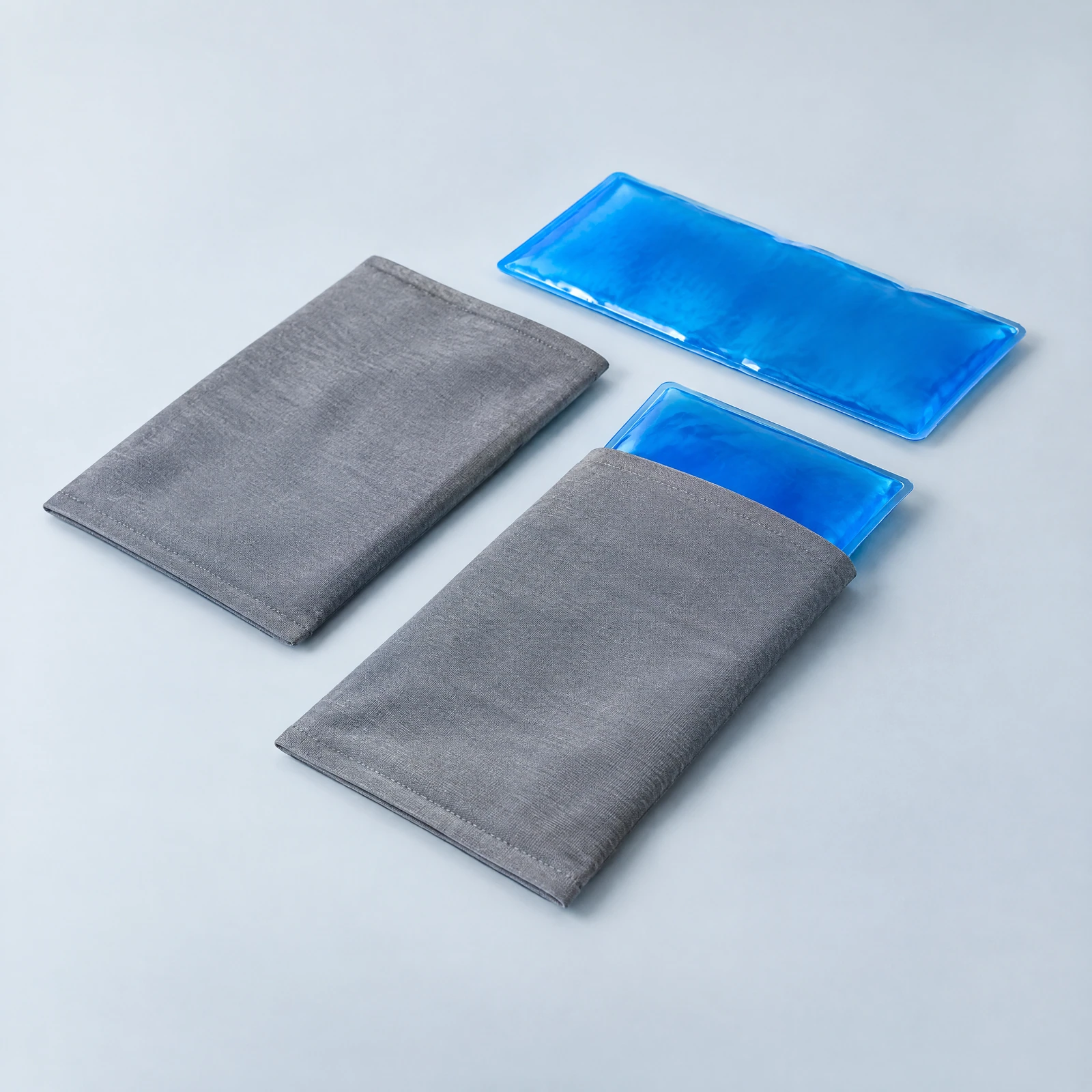 Two blue hot/cold packs shown beside two gray sleeves, one pack partly inside a sleeve